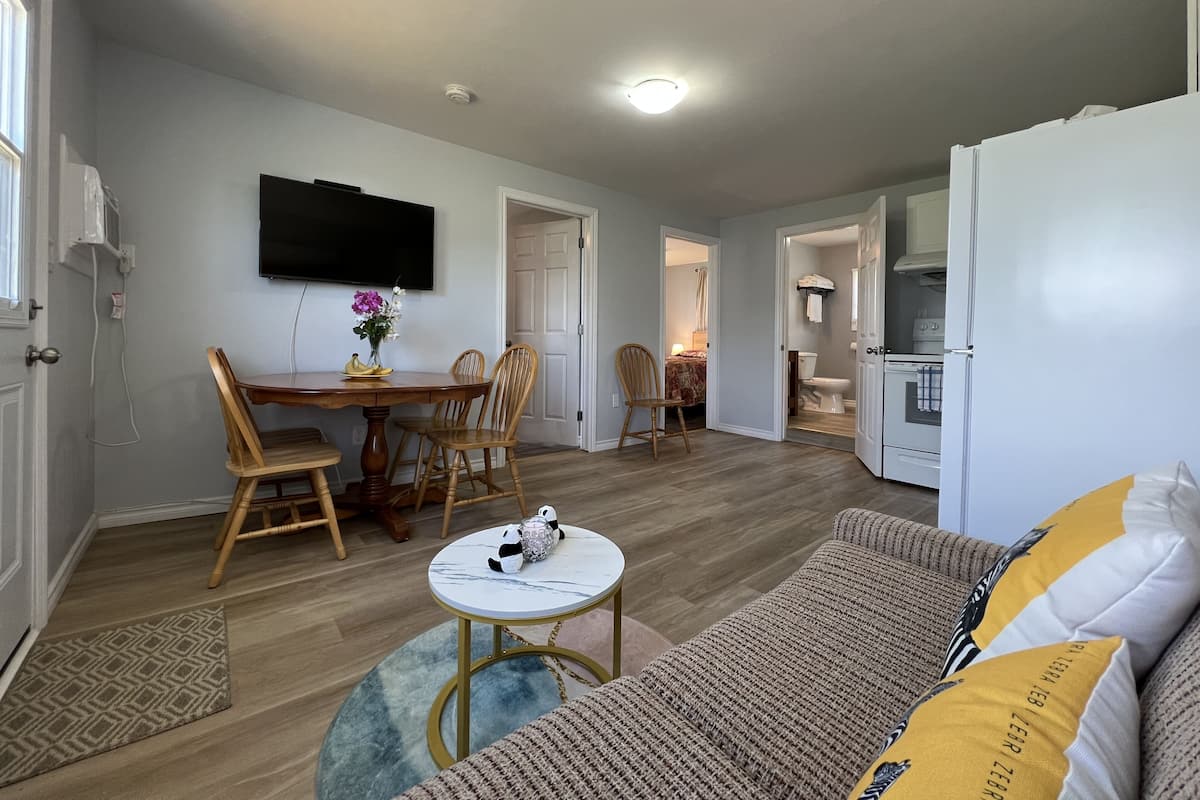 A compact living space with a dining area, a sofa, a small table, and a kitchen area.