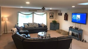 A living room with a sofa, a coffee table, a TV, and a dog.