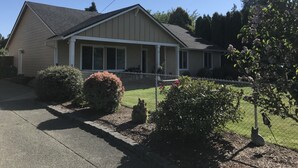 A single-story house with a sloped roof, a front porch, and a fenced yard.