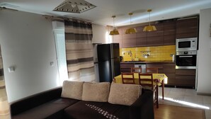 A modern kitchen with a refrigerator, microwave, and oven. There is a dining table with chairs and a sofa in the living area. - Renovated apartment (Marseille)
