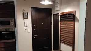 A room with a dark wooden door, a built-in microwave, a small refrigerator, and a wooden bench. - Renovated apartment (Marseille)