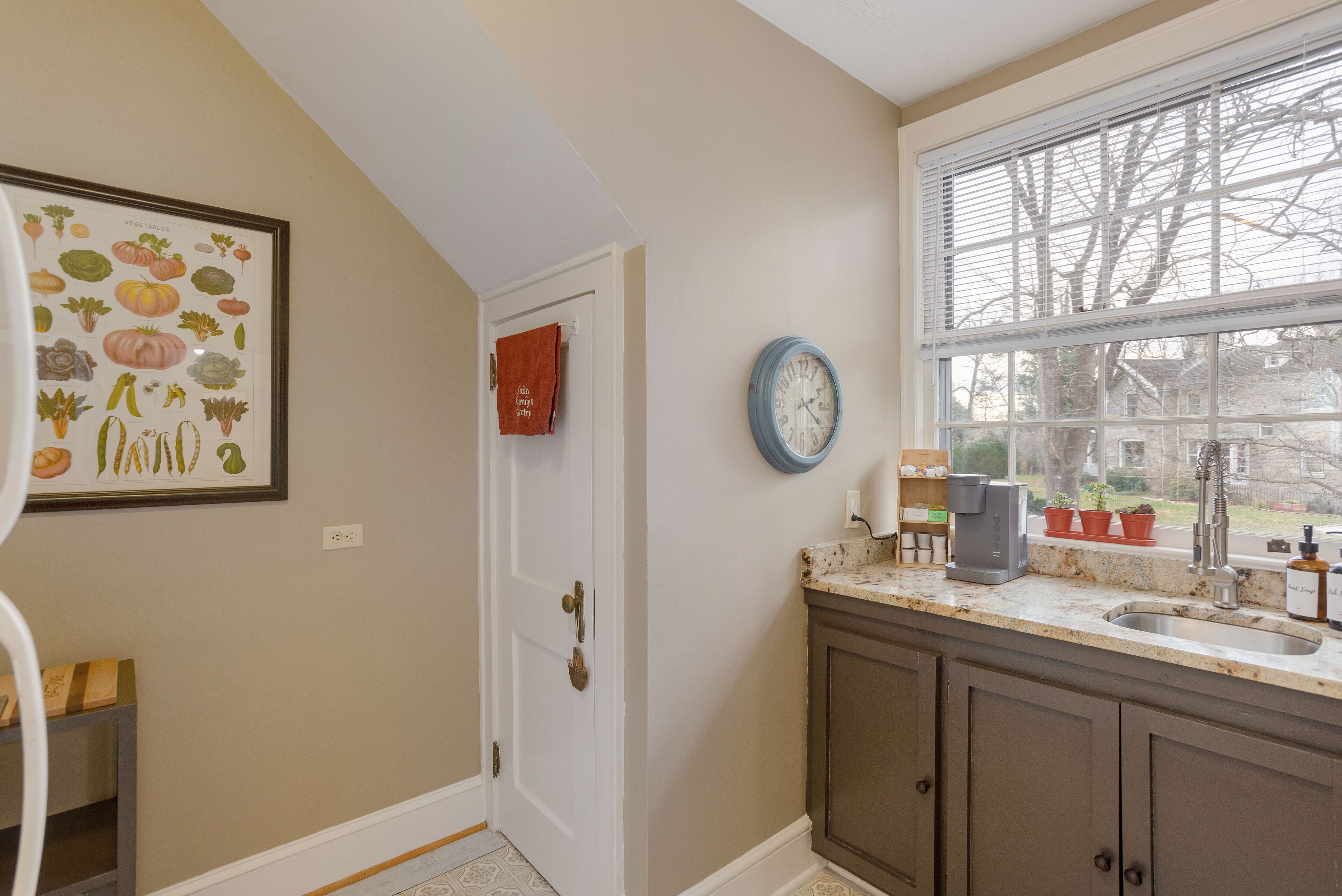 A kitchen with a sink, a clock, and a door.