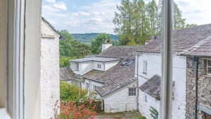 A traditional stone building with a sloped roof, white walls, and a small window. - Bowmanstead Cottage - quirky & cosy traditional village cottage (Coniston)