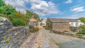 A stone pathway leading to traditional stone buildings with a clear sky above. - Bowmanstead Cottage - quirky & cosy traditional village cottage (Coniston)