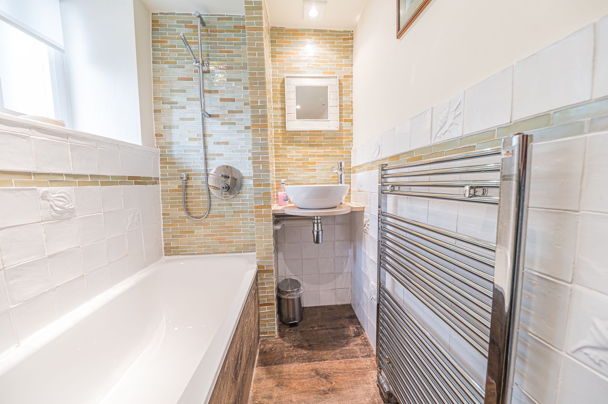 A bathroom with a bathtub, a shower, a sink, and a towel rack.