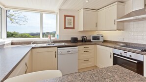 A modern kitchen with a built-in dishwasher, a microwave, and a stove. There is a window providing a view of the outdoors. - Drawing Room, grand apartment with stunning lake views across Beatrix Potter country (Far Sawrey)