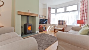 A cozy living room with a fireplace, a television, and comfortable seating. - Green Croft - garden cottage in Coniston village (CONISTON)