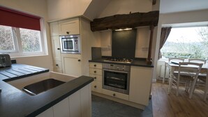 A compact kitchen with a built-in oven, a stovetop, and a sink. - Poppy Cottage, village cottage with lake views (Coniston)
