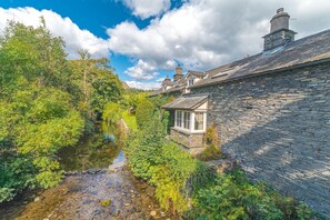 A stone building with a small window overlooking a stream. - Smithy Cottage - large village cottage for 6 with riverside garden (Coniston)