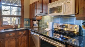A kitchen with wooden cabinets, a stainless steel stove, a microwave, and a dishwasher. - Elegant 4BR Condo for 8 • Ski Views • Walk to Village • Spa & Shuttle (Mont-Tremblant)