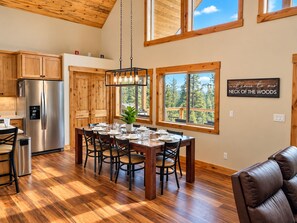 A modern kitchen with a stainless steel refrigerator, wooden cabinets, and a dining area with a wooden table and chairs.