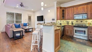 A modern kitchen with wooden cabinets, a built-in oven, and a large island. - Huge Home w/ Gameroom, Patio, & Secret Room! (Dallas)