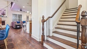 A spacious living area with a wooden staircase, a fireplace, and a dining area. - Huge Home w/ Gameroom, Patio, & Secret Room! (Dallas)