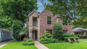 A two-story brick house with a stone entrance, surrounded by well-maintained lawns and trees. - Huge Home w/ Gameroom, Patio, & Secret Room! (Dallas)