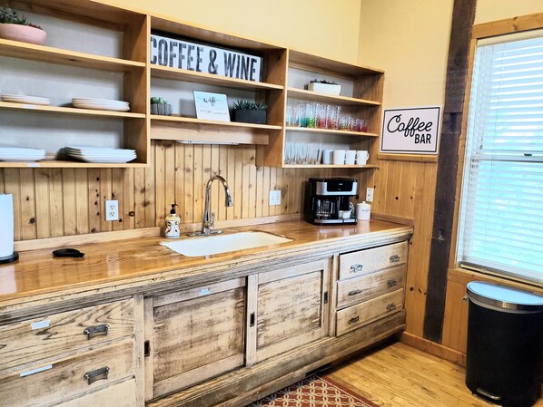 A kitchen with wooden cabinetry, a coffee bar sign, and a coffee machine.