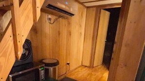 A compact wooden cabin with a kitchenette, including a microwave and a small stove.