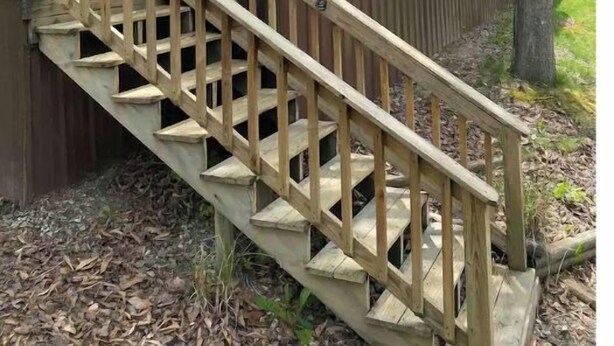 A wooden staircase leading to a cabin with a balcony.