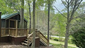 A cabin with a wooden deck and a staircase leading to a covered porch.