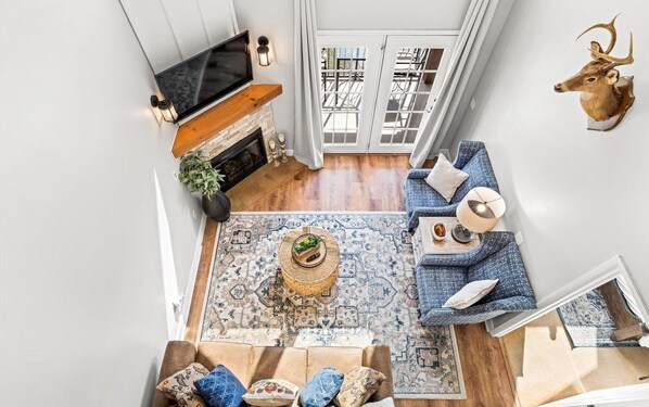 A spacious living room with a fireplace, a television, a blue sofa, and a decorative deer head on the wall.