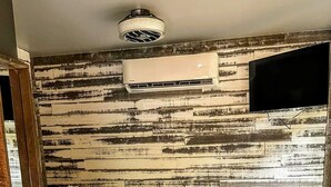 A bedroom with a bed, a ceiling fan, and a wall-mounted air conditioner. - The Oaklyn Container ~ Hocking Hills ~ Hot tub ~ Firepit ~ Wifi (Logan)