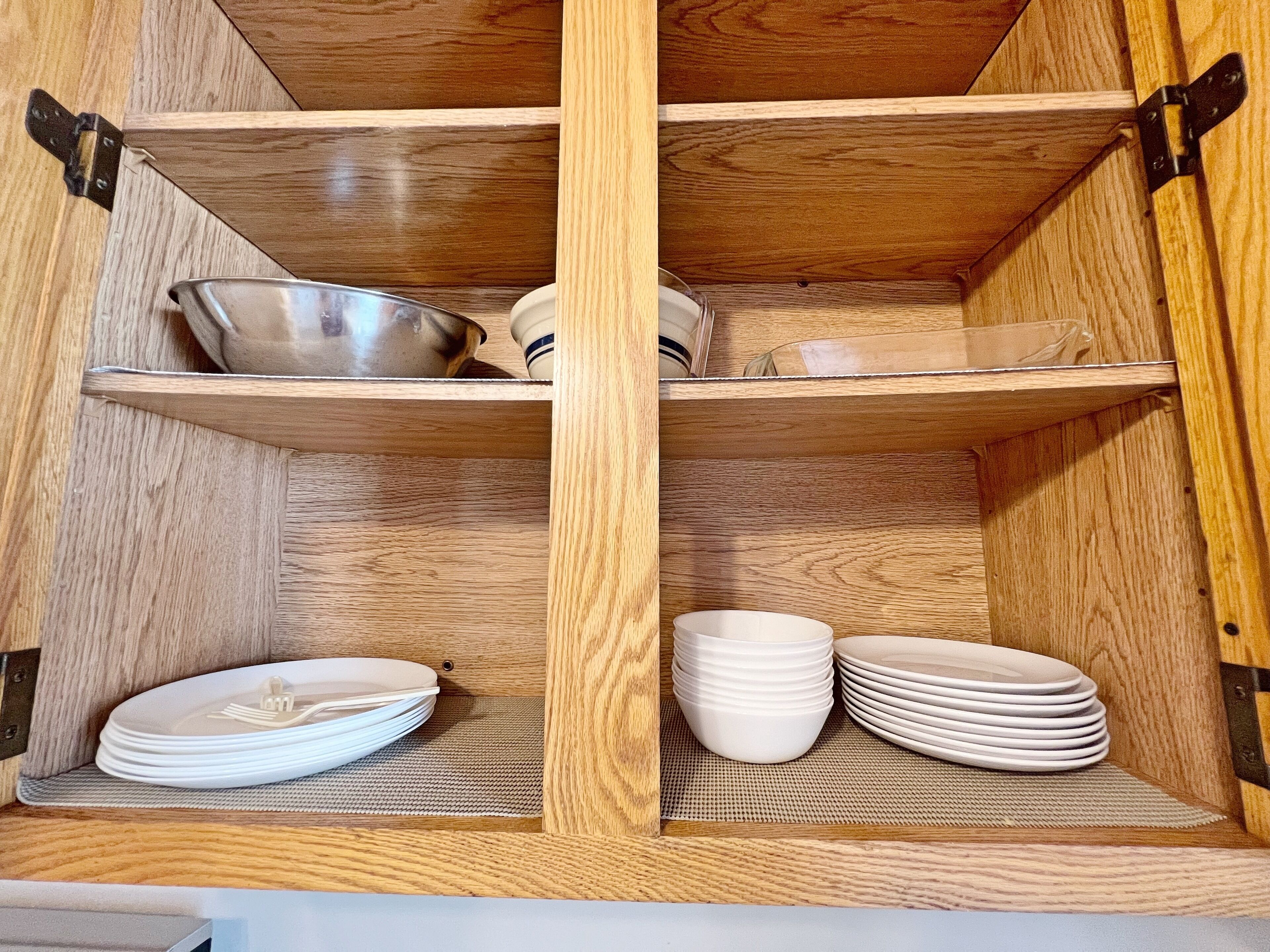 A wooden cabinet with two shelves, each holding plates and bowls.