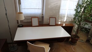 Une salle de conférence avec une grande table, deux chaises, un lampadaire et une plante en pot.