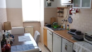Une cuisine compacte comprenant un coin repas, un four encastré et une fenêtre laissant entrer la lumière naturelle.