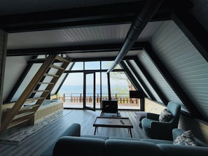 A modern loft bedroom with a large skylight, a wooden staircase, and a view of the outdoors. - Dibektaş Modi Bungalov (Sapanca)