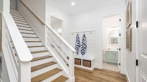 Un escalier avec des rampes blanches et des marches en bois menant à une pièce dont le mur est blanc et qui possède une petite fenêtre.