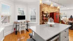 A modern kitchen with a central island, white cabinetry, and a brick accent wall.