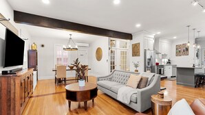 A modern living room with a grey sofa, wooden coffee table, and a TV on a wooden cabinet.