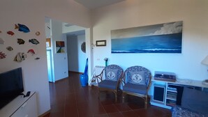 A living room with a flat-screen TV, two armchairs, a coffee table, and a bookshelf. - Castiglioncello Baia del Quercetano, the sea in the eyes. (Rosignano Solvay-Castiglioncello)