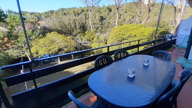 A balcony with a table and chairs, overlooking a forested area. - Castiglioncello Baia del Quercetano, the sea in the eyes. (Rosignano Solvay-Castiglioncello)