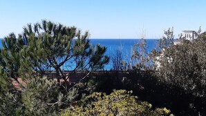 A coastal view with a clear sky, a bridge, and a building with a bell tower in the background. - Castiglioncello Baia del Quercetano, the sea in the eyes. (Rosignano Solvay-Castiglioncello)