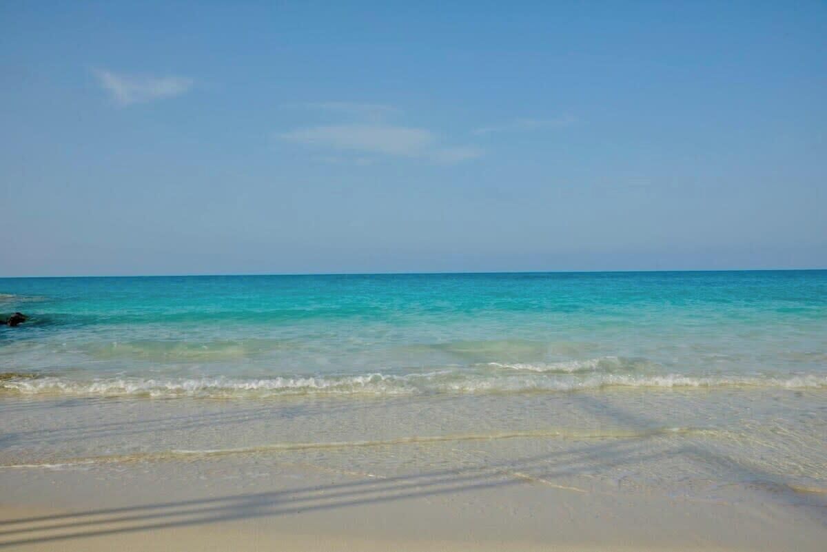 A beach with clear turquoise water and a sandy shore.