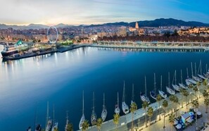 Ein Yachthafen mit vertäuten Booten, ein Riesenrad und eine Stadtkulisse im Hintergrund.