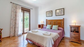 A bedroom with a bed, a nightstand, a dresser, a window with curtains, and two wall-mounted pictures. - Casa Rural La Promesa Álora by Ruralidays (Málaga)