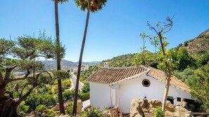 A white building with a tiled roof, surrounded by trees and hills. - Casa Rural La Promesa Álora by Ruralidays (Málaga)