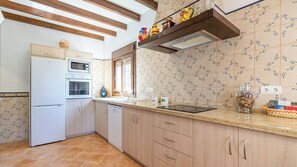 A kitchen with wooden cabinets, a white refrigerator, a microwave, an oven, and a sink. - Casa Rural La Promesa Álora by Ruralidays (Málaga)