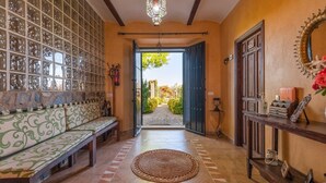 Un couloir avec un banc, un tapis tissé et une porte donnant sur l’extérieur.