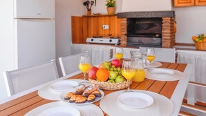 A breakfast setting with a table set for two, including croissants, fruit, and orange juice.