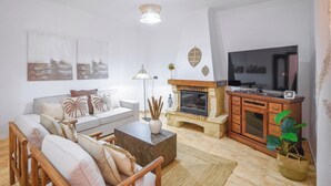 A modern living room with a sofa, coffee table, fireplace, TV, and decorative items.