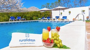 A poolside area with lounge chairs, umbrellas, and a towel with 'ruralidays' branding.
