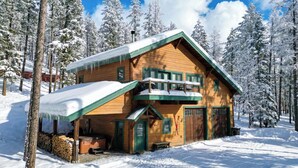 Une cabane en bois dotée d’un balcon, entourée d’arbres couverts de neige.