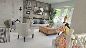 A living room with a white sofa, a colorful horse sculpture, and a large window. - Artistic get away (Hampton Bays)