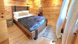 A wooden-paneled bedroom with a bed, a small rug, and a basket. - Artistic get away (Hampton Bays)