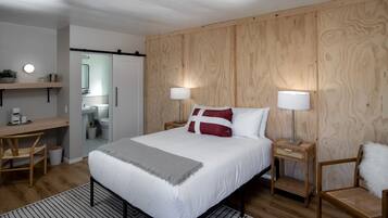 A bedroom with a bed, bedside tables, a desk, and a chair.