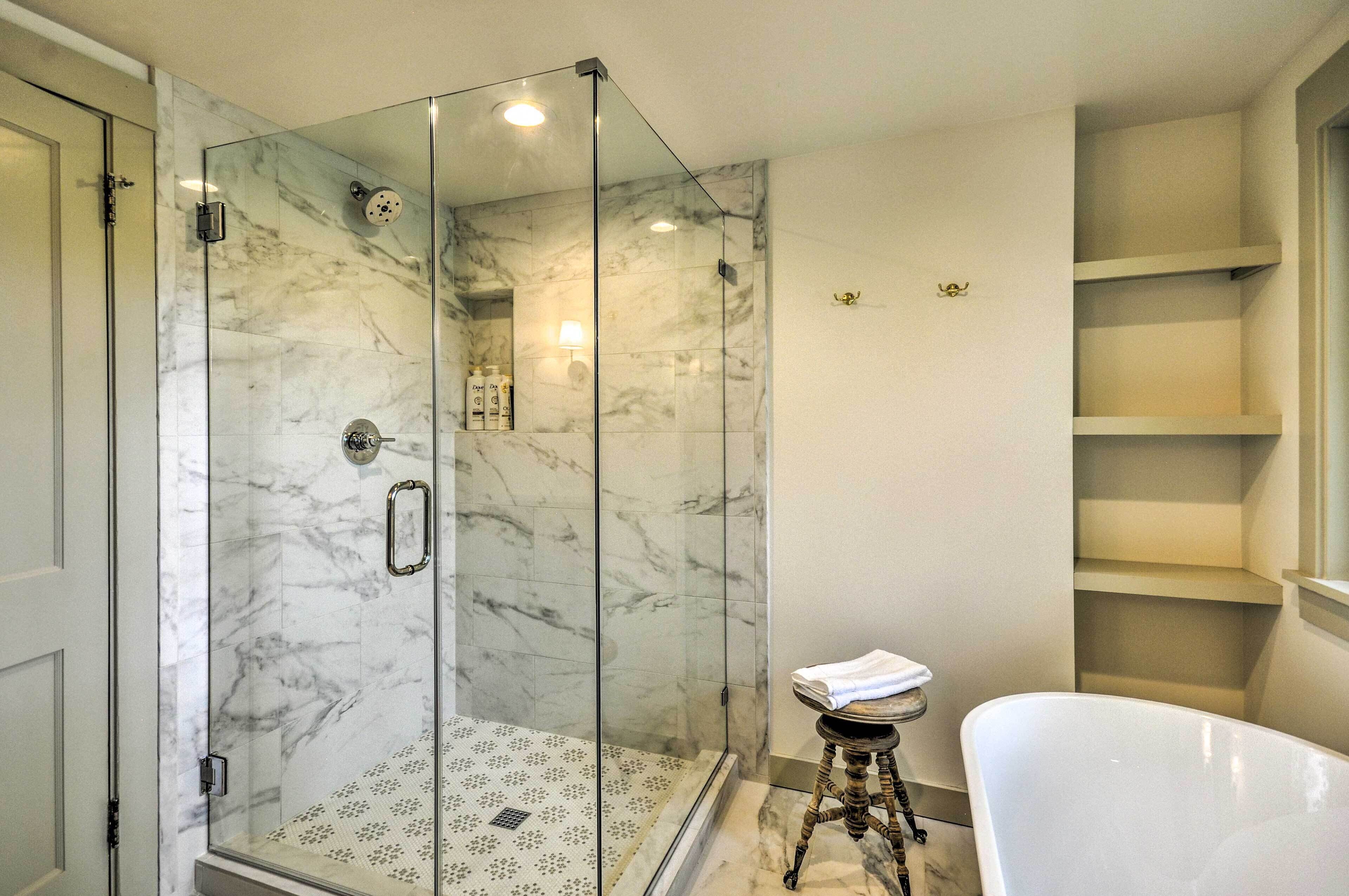 Ein modernes Badezimmer mit einer gläsernen Duschkabine, einer freistehenden Badewanne und Marmorböden.