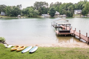 A lakeside property with a dock, kayaks, and a covered seating area.