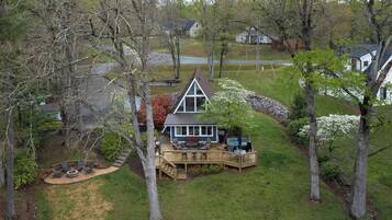 Une maison avec une terrasse, un jacuzzi et un foyer extérieur dans le jardin.